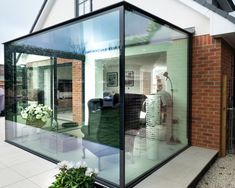 a large glass house sitting on top of a white tiled floor next to a brick building