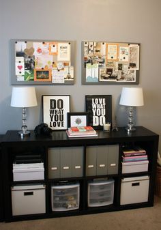 two pictures are hanging on the wall above a black table with drawers and bins