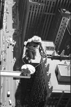 a man is hanging from the side of a tall building while holding onto a rope