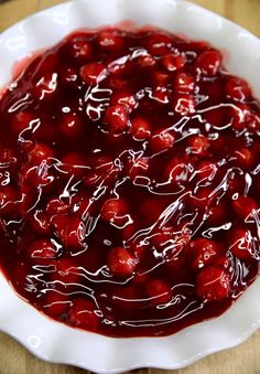 a white bowl filled with cherries on top of a wooden table