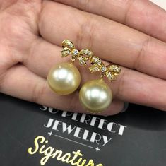 We are presenting you A PERFECT PAIR OF CREAMY WHITE SOUTH SEA PEARLS! WITH EXCELLENT LUSTER. Accented with 22 pieces or superb quality, F/VS sparkling diamonds. SET IN HANDCRAFTED, 18K SOLID YELLOW GOLD SCREWED BACK EARRINGS. DANGLING BOW DESIGN, ELEGANT AND CUTE! IN CASE OF RETURN FOR US BUYERS. BUYERS MAY SEND THE ITEMS BACK TO OUR US-BASED OFFICE IN SALT LAKE CITY, UTAH ONLY ONE ITEM AVAILABLE!! NO DUPLICATES!! WHAT YOU SEE IN THE PICTURES IS WHAT YOU WILL GET SOLIDLY HANDCRAFTED EARRINGS! S Aaa Quality Round Pearl Earrings For Wedding, Aaa Quality Pearl Earrings For Wedding, Exquisite Aaa Quality Pearl Earrings For Wedding, Aaa Quality Exquisite Pearl Earrings For Wedding, Luxury Round Pearl Earrings For Wedding, Luxury Gold Round Bridal Earrings, Luxury Pearl Bridal Earrings Gift, Yellow Pearl Wedding Jewelry, Elegant Yellow Bridal Earrings For Wedding