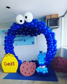 an arch made out of balloons with eyes and mouth on the top, in front of a sign that says cookie's