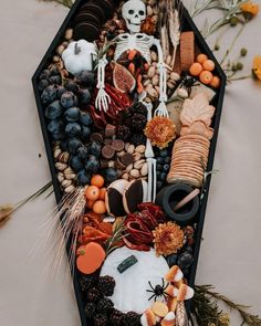 a boat filled with lots of halloween decorations on top of a white table covered in leaves and flowers