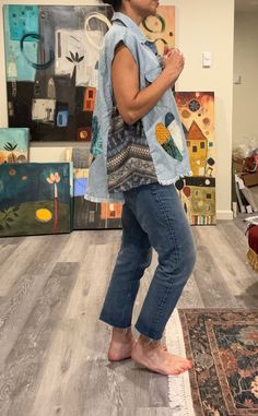 a woman standing on top of a rug in front of paintings and holding a cell phone