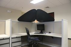 an office cubicle with two computer screens and chairs