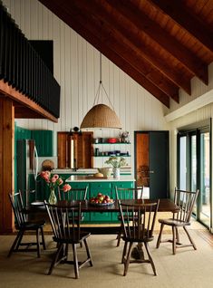 a dining room with green cabinets and wooden chairs