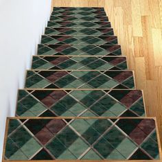 a set of stairs with green and brown tiles on the bottom, along with wood flooring