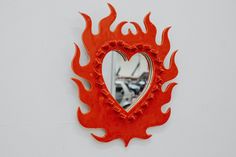 a red heart shaped mirror mounted to the side of a wall