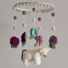 a crocheted toy horse is hanging from a circular mobile with flowers on it