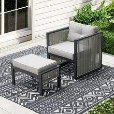 two chairs and a footstool sitting on a rug in front of a house