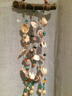 a wind chime with shells and beads hanging from it's side on a wall