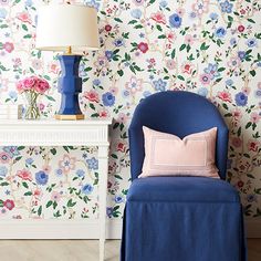 a blue chair sitting next to a white table with a lamp on top of it