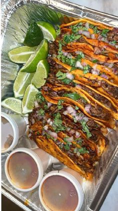 mexican food is prepared and ready to be eaten on a tray with lime wedges