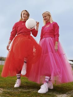 two women in red and pink tulle skirts holding a white ball