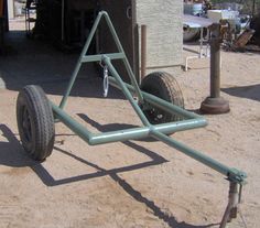 an upside down metal object sitting on top of a dirt field next to a building