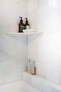 a shelf in the corner of a bathroom with soap and lotion