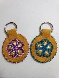 two handmade key chains with beaded designs on them sitting next to each other