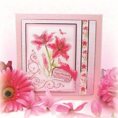 a card with pink flowers on it next to some pink daisies and one red flower