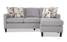 a gray couch with pillows on it and a footstool in front of it