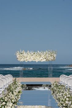 an outdoor ceremony setup with white flowers and greenery on the water's edge