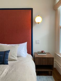 a red headboard in a bedroom next to a night stand with two lamps on it