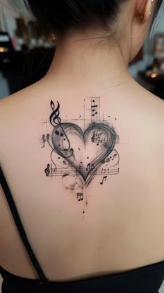 a woman's back with musical notes and a heart tattoo on her upper shoulder