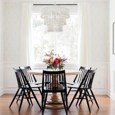 a dining room table with four chairs and a chandelier hanging from the ceiling