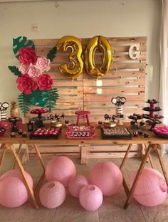 a table topped with lots of pink and gold balloons next to a sign that says 30