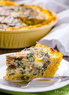 a slice of quiche on a plate with a fork next to the casserole