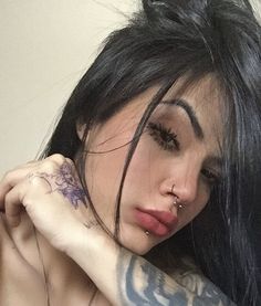 a close up of a person with tattoos on their arms and shoulder, holding a cell phone to her ear