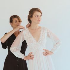 two women standing next to each other with their hands on their hipss, one wearing a white and black dress