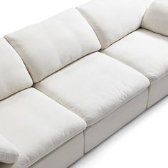 a large white couch with pillows on it's back end and arm rests against the wall