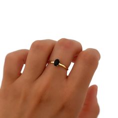 a woman's hand with a gold ring and black diamond on the middle finger