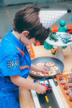 a little boy that is standing in front of a table with some doughnuts