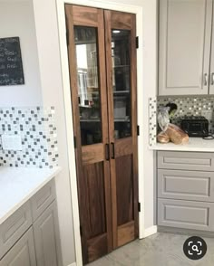 a kitchen with two wooden doors and white cabinets in the corner, along with a counter top