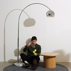 a man sitting on the floor with tennis balls in front of him and a lamp behind him