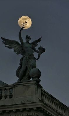 a statue on top of a building with the moon in the background