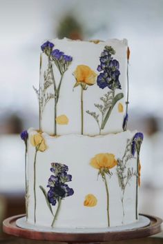 a three tiered cake decorated with yellow and purple flowers