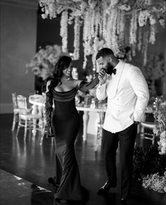 a man and woman standing next to each other in front of a chandelier