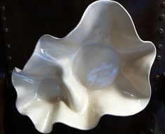 a white flower shaped bowl sitting on top of a black table next to a wall