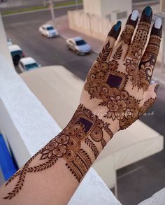 a woman's hand with henna on it and cars parked in the background