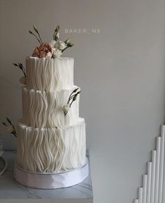 a three tiered white cake with flowers on top