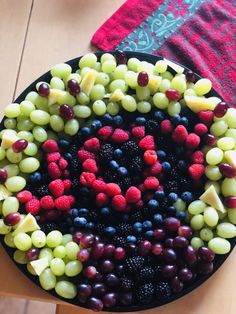 a plate filled with grapes, raspberries and other fruits