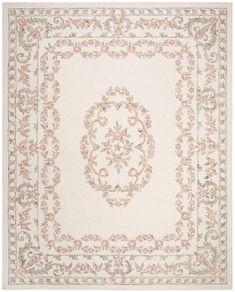 a white rug with pink flowers and scrolls on the border, in an ornate frame