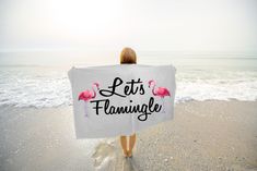 a woman holding a towel that says let's flamingo