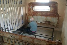 an old man is sitting on the bed frame in his home made out of wood and metal