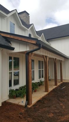 an outside view of a white house with wood trimmings and plants on the side