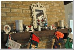 christmas stockings hung on the mantle in front of a brick wall with a mirror and other decorations