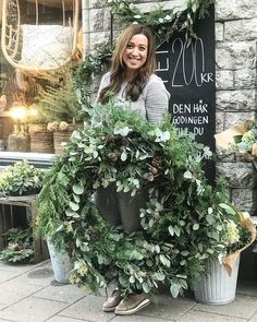 a woman standing in front of a store holding a wreath