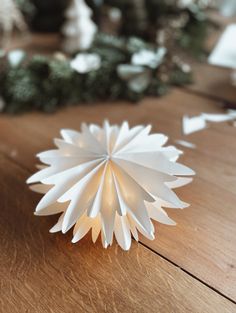 a white paper flower sitting on top of a wooden table